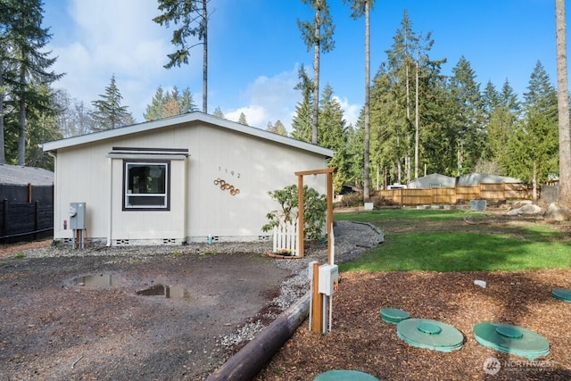 view of side of property with crawl space, fence, and a yard