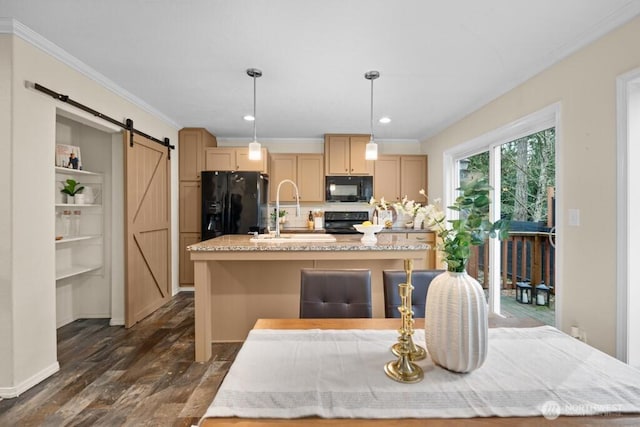 kitchen featuring a barn door, ornamental molding, a sink, an island with sink, and black appliances