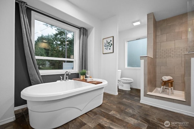 full bathroom with plenty of natural light, a freestanding bath, toilet, and wood finished floors