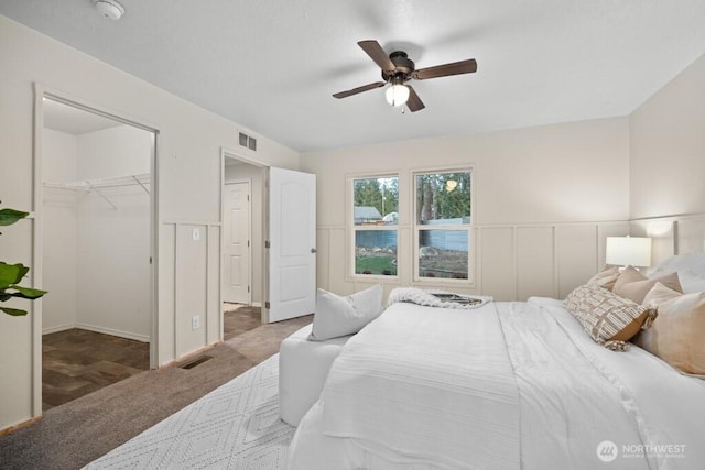 bedroom with a walk in closet, carpet, visible vents, and a decorative wall