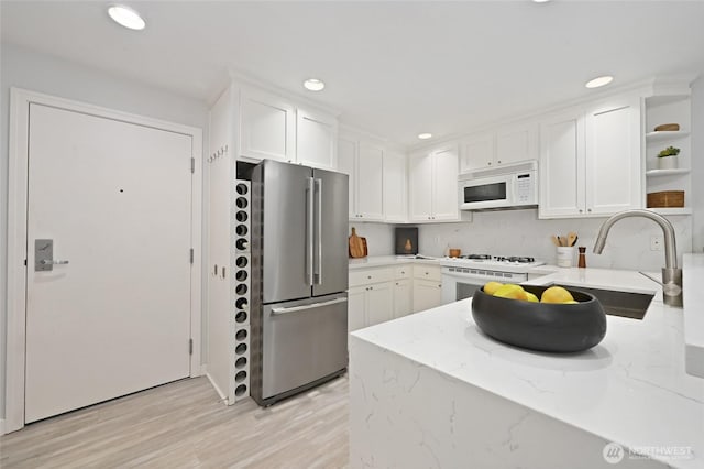 kitchen featuring light wood finished floors, open shelves, white cabinets, white appliances, and a sink