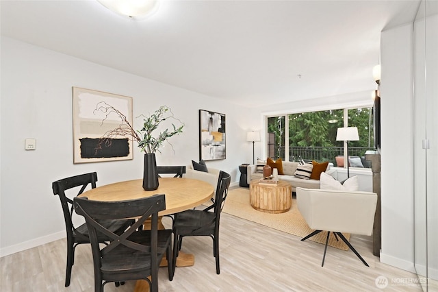 dining space with light wood-type flooring and baseboards