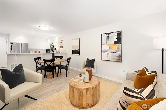 living area with recessed lighting, visible vents, baseboards, and light wood finished floors