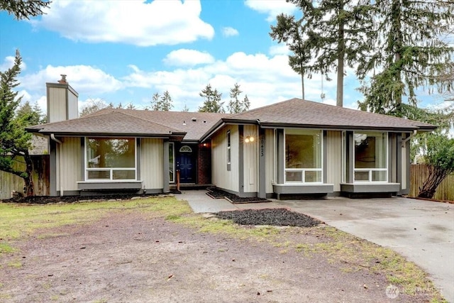 single story home with a shingled roof, a chimney, and fence