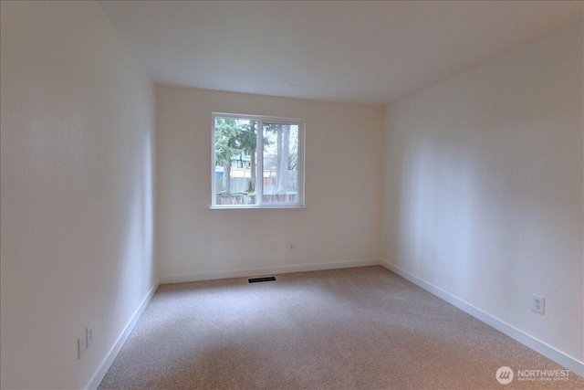 spare room featuring visible vents, baseboards, and light carpet