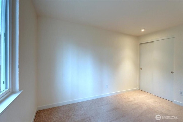 unfurnished bedroom featuring a closet, baseboards, and carpet