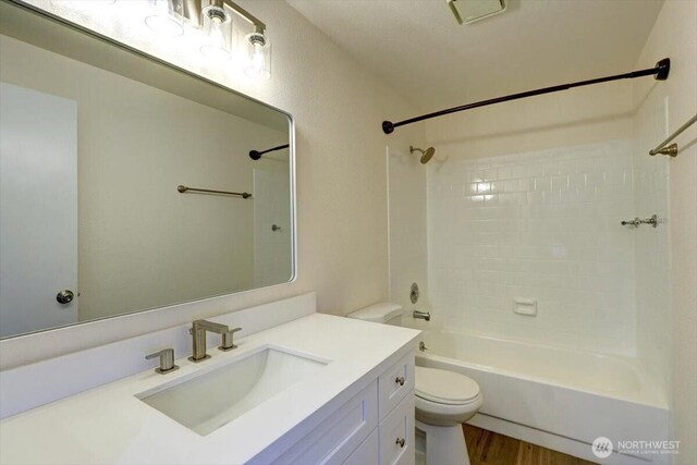 full bathroom with toilet, wood finished floors, vanity, and shower / tub combination