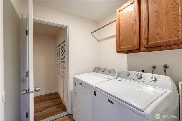 laundry area featuring washer and dryer, baseboards, cabinet space, and wood finished floors