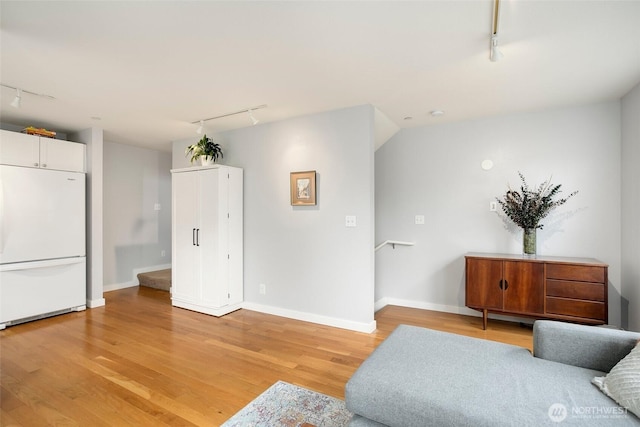 living room featuring baseboards, light wood-type flooring, and track lighting