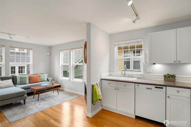 kitchen featuring a sink, light wood-style floors, open floor plan, dishwasher, and track lighting