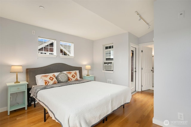 bedroom with rail lighting, visible vents, wood finished floors, cooling unit, and baseboards