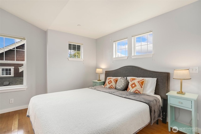 bedroom featuring vaulted ceiling, baseboards, and wood finished floors