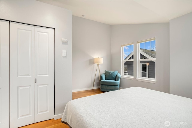 bedroom featuring lofted ceiling, light wood finished floors, baseboards, and a closet