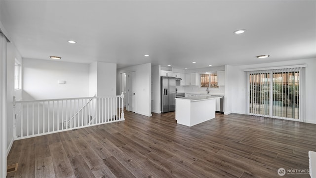 kitchen with a center island, open floor plan, dark wood-style flooring, and white cabinetry