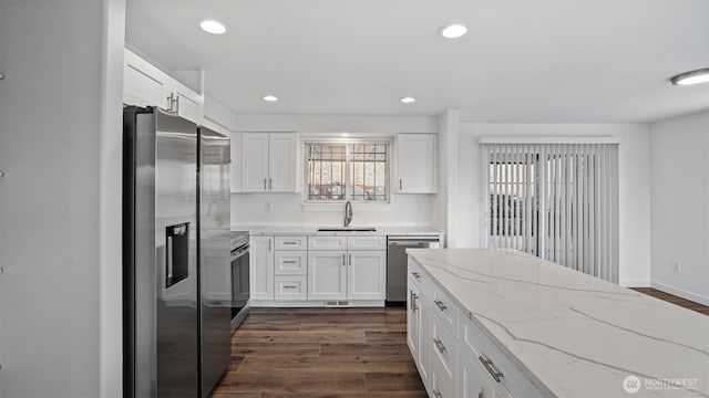 kitchen with a sink, recessed lighting, stainless steel appliances, white cabinetry, and dark wood-style flooring