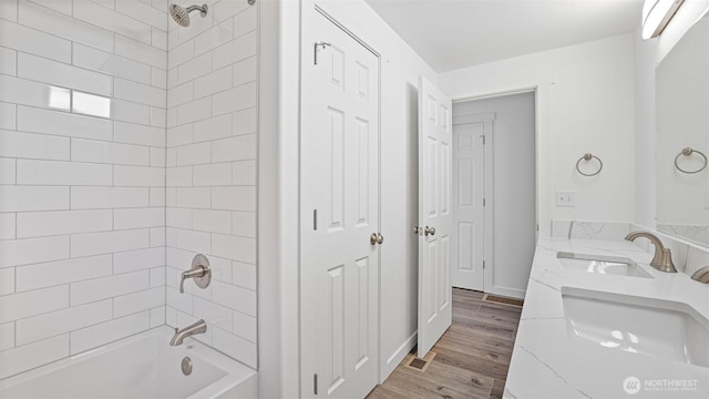 bathroom with shower / washtub combination, wood finished floors, baseboards, and a sink