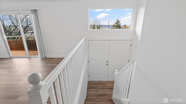 staircase with a towering ceiling, baseboards, and wood finished floors