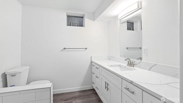 bathroom featuring vanity, toilet, wood finished floors, and baseboards