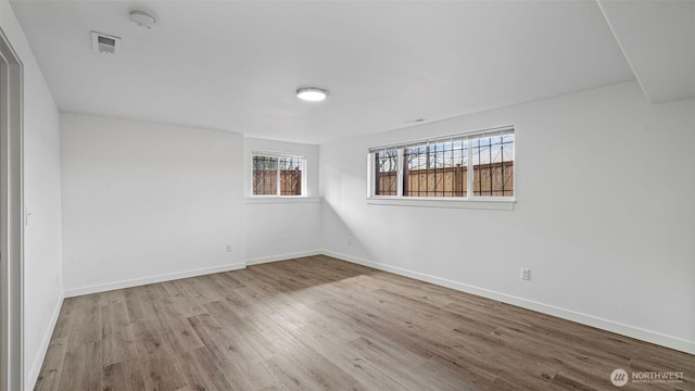 empty room with visible vents, baseboards, and wood finished floors