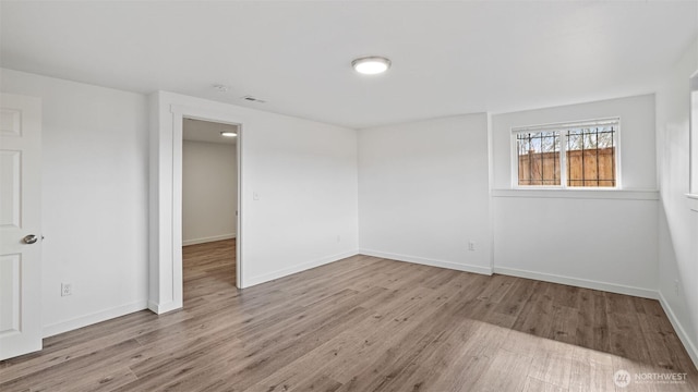 spare room with visible vents, baseboards, and wood finished floors