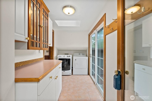 laundry area featuring cabinet space, light tile patterned floors, a skylight, and separate washer and dryer