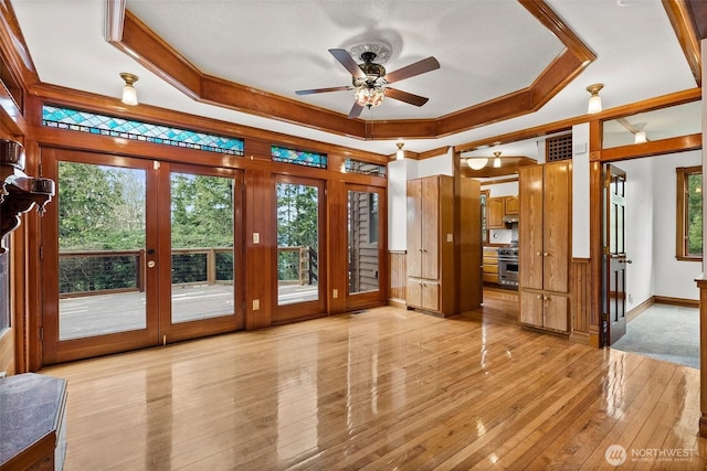 unfurnished sunroom with ceiling fan, a tray ceiling, and a healthy amount of sunlight