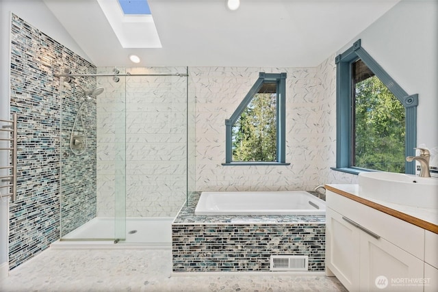 bathroom featuring lofted ceiling with skylight, a garden tub, a shower stall, and vanity