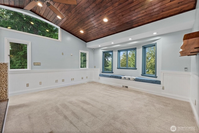 spare room featuring carpet, wooden ceiling, a wainscoted wall, and lofted ceiling