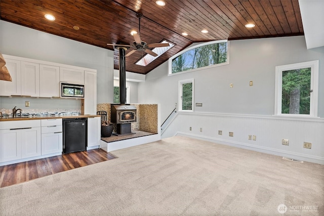 kitchen featuring high vaulted ceiling, wood ceiling, fridge, stainless steel microwave, and carpet