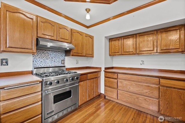 kitchen with under cabinet range hood, premium range, ornamental molding, light wood finished floors, and brown cabinetry