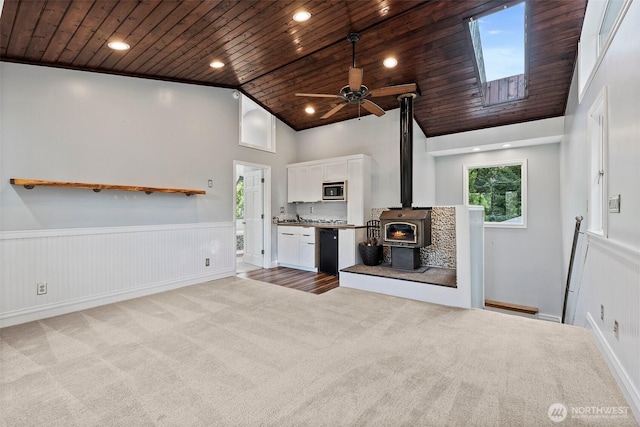 kitchen with wood ceiling, stainless steel microwave, white cabinets, and carpet flooring