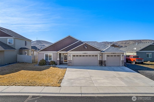 view of front of home featuring an attached garage, fence, driveway, stone siding, and a front lawn