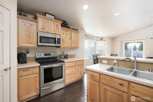 kitchen featuring dark wood-style floors, stainless steel appliances, light countertops, light brown cabinetry, and a sink