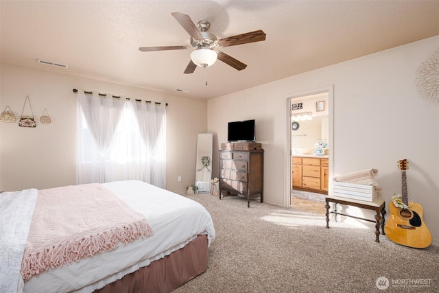 bedroom with light colored carpet, visible vents, connected bathroom, and ceiling fan