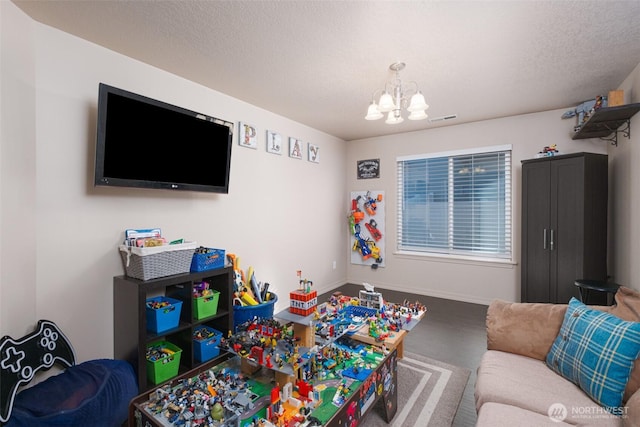 rec room with visible vents, a notable chandelier, a textured ceiling, and baseboards