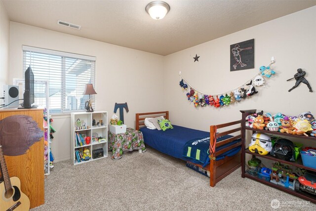 carpeted bedroom featuring visible vents and a textured ceiling