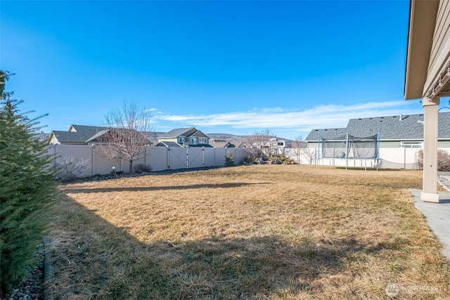 view of yard with a trampoline and a fenced backyard