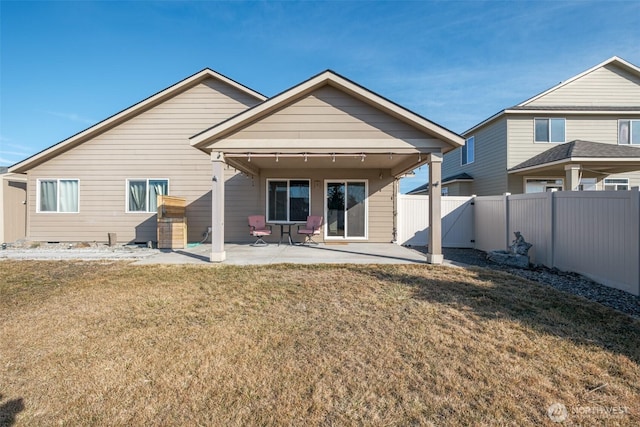 rear view of property featuring a patio area, a yard, and fence