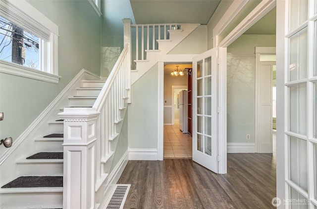 stairway featuring wood finished floors, baseboards, visible vents, french doors, and a chandelier