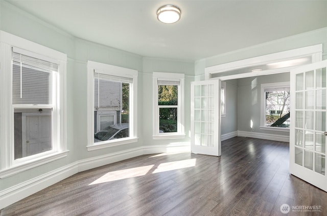 empty room featuring french doors, baseboards, and dark wood finished floors