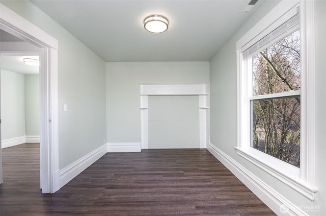 empty room with visible vents, baseboards, and dark wood finished floors