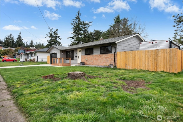 view of front facade featuring a front yard, concrete driveway, brick siding, and fence