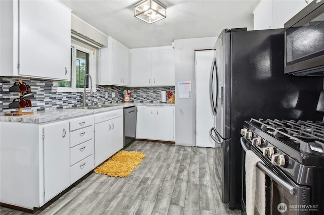 kitchen featuring light wood finished floors, decorative backsplash, range with gas stovetop, dishwasher, and a sink