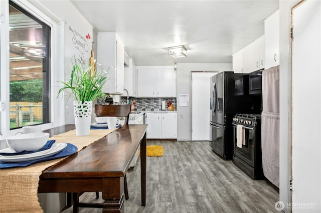 kitchen with light wood finished floors, light countertops, decorative backsplash, white cabinetry, and black appliances