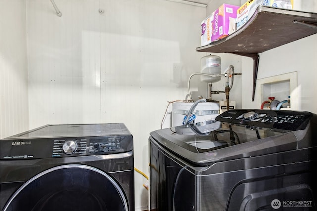 washroom featuring water heater, laundry area, and washer and clothes dryer