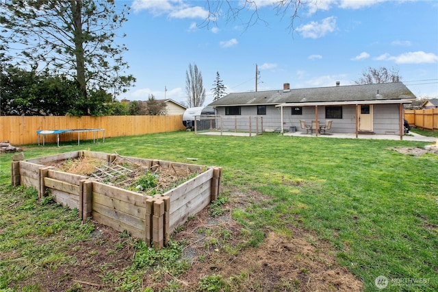 view of yard featuring a garden, a trampoline, a fenced backyard, and a patio