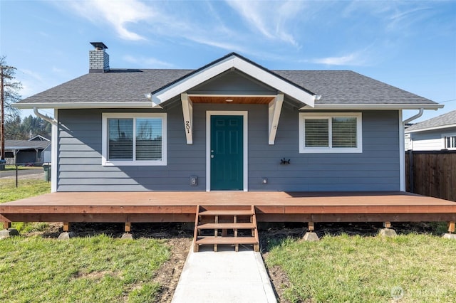 bungalow-style house featuring a deck, roof with shingles, a chimney, and fence