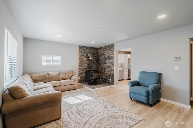 living room featuring a wood stove, light wood-style flooring, baseboards, and recessed lighting