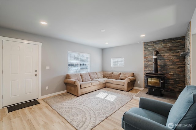 living area with recessed lighting, wood finished floors, a wood stove, and baseboards