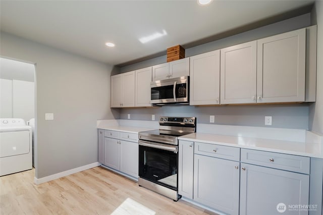 kitchen featuring stainless steel appliances, washing machine and clothes dryer, light countertops, and light wood-style floors